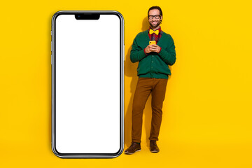 Full size photo of handsome guy hold telephone huge empty space screen banner isolated on yellow color background