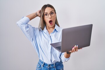 Young woman working using computer laptop crazy and scared with hands on head, afraid and surprised...