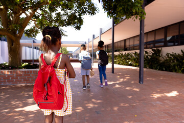 Happy african american schoolchildren wearing school bags in school yard