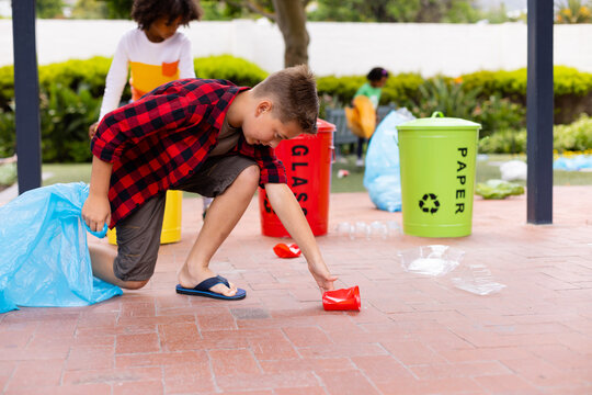Happy diverse schoolchildren cleaning and recycling waste at school