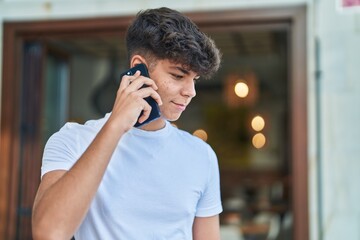 Young hispanic teenager smiling confident talking on the smartphone at street