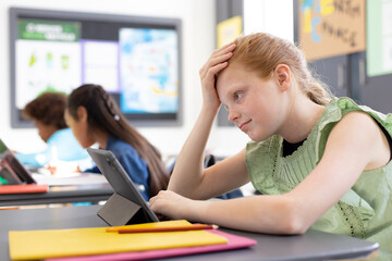 Happy diverse schoolchildren sitting at desks in school classroom