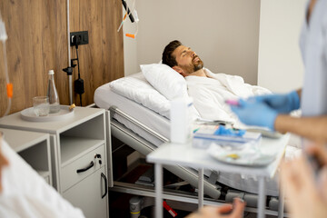 Obraz premium Man resting on medical bed, waiting for some procedures in a ward. Rehabilitation and medical support concept