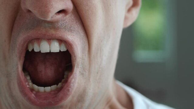 Close up mouth of irritated aggressive man shouting, portrait of screaming aggressive male person, feeling anger and stress, bad mood. Closeup male annoyed showing aggression.