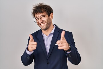 Hispanic business man wearing glasses pointing fingers to camera with happy and funny face. good energy and vibes.