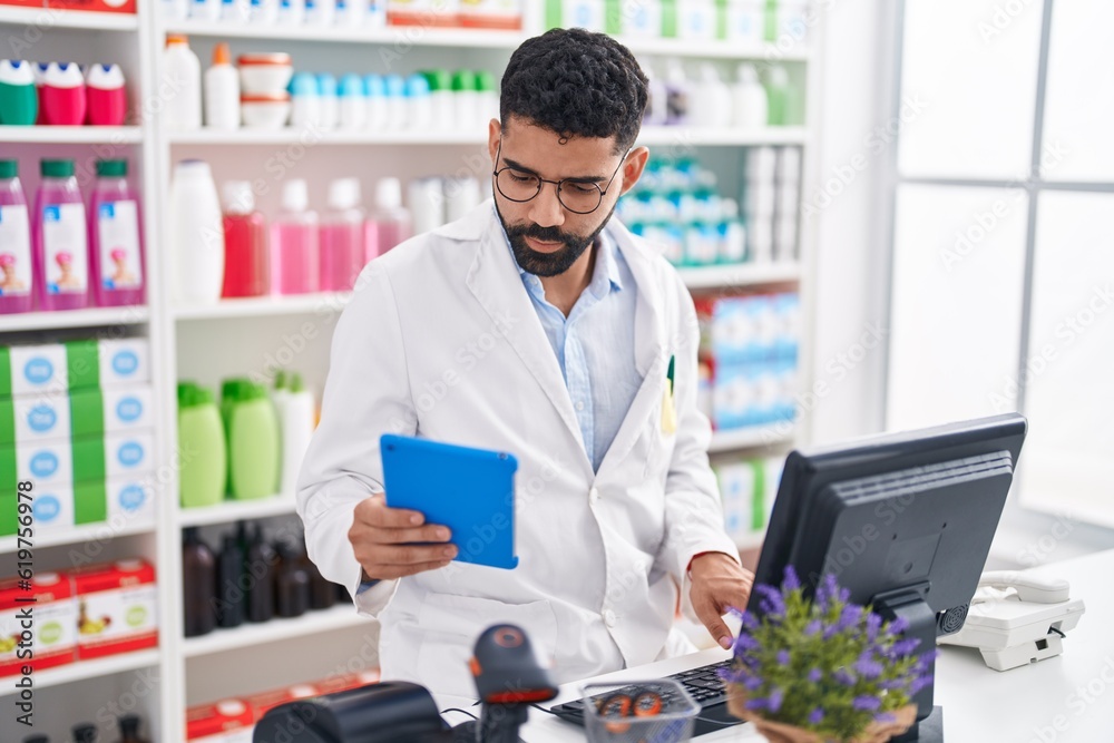 Sticker Young arab man pharmacist using touchpad and computer at pharmacy