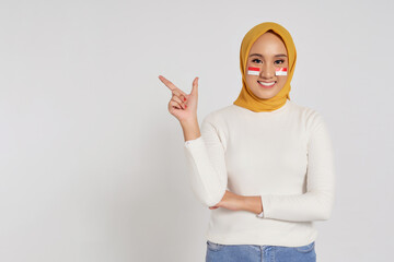 Portrait of smiling young Asian Muslim woman wearing a hijab showing place for your advertisement...
