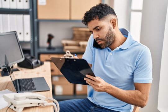 Young hispanic man ecommerce business worker talking on the smartphone at office