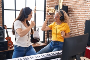 Obraz premium Two women musicians listening to music dancing at music studio