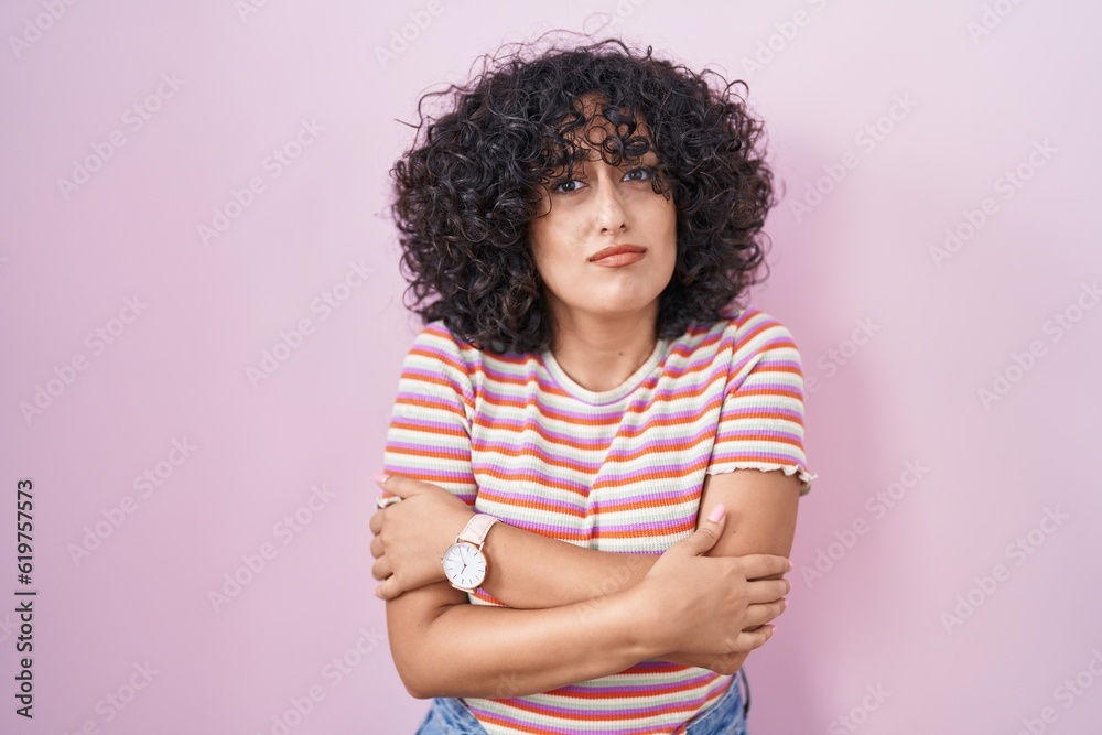 Poster young middle east woman standing over pink background shaking and freezing for winter cold with sad 