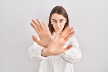 Young caucasian woman standing over isolated background rejection expression crossing arms and...