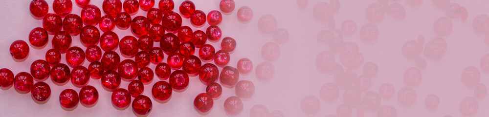 red handicraft items, jewelry, beads, DIY background. Plastic acrylic glass beads of different shapes and colors for making brooches, pendants, collars. Blur effect. Weak focus.