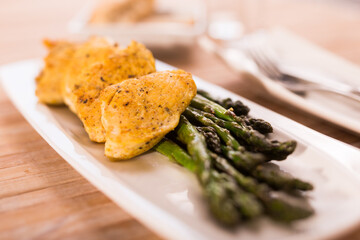 fried chicken breast pieces with asparagus on white plate