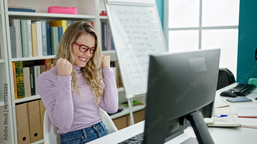 Poster Young blonde woman student using computer with winner expression at classroom