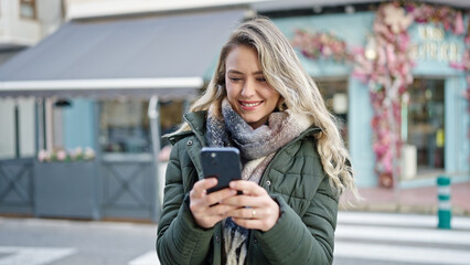 Fototapeta premium Young blonde woman smiling confident using smartphone at coffee shop terrace