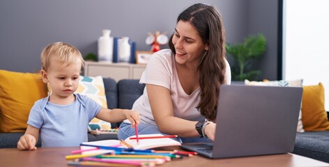 Mother and son drawing on notebook using laptop at home