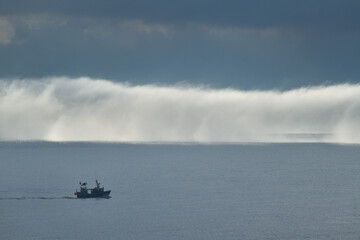 A bank of fog on the sea with a boat in the foreground