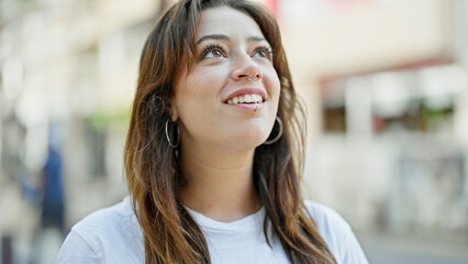 Young beautiful hispanic woman smiling confident looking to the sky at street