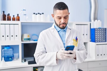 Young latin man scientist using smartphone at laboratory