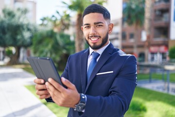 Fototapeta premium Young latin man business worker smiling confident using touchpad at park