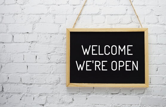 Welcome We are Open typography text on blackboard hanging against on the wall background