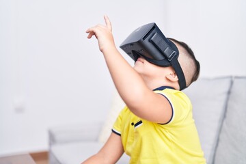 Adorable hispanic boy playing video game using virtual reality glasses at home