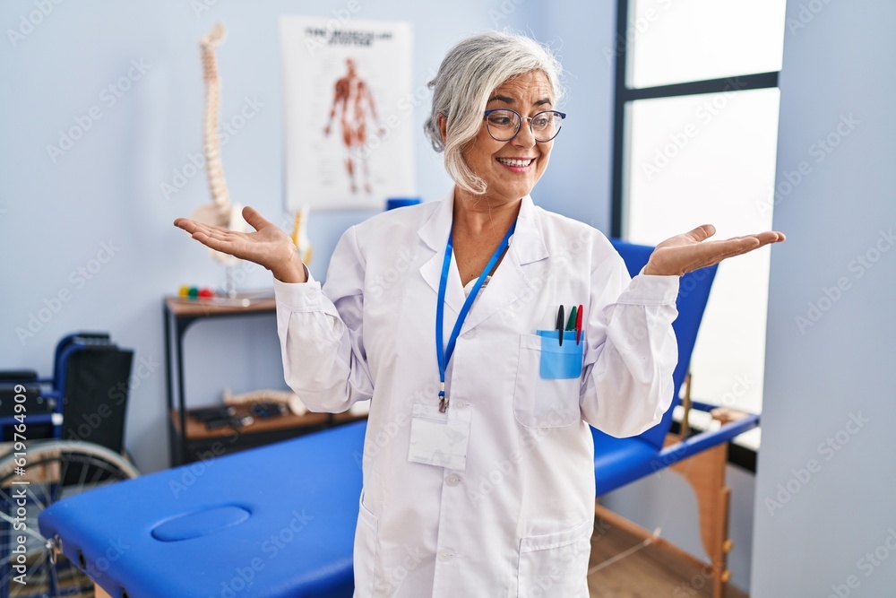 Sticker middle age woman with grey hair working at pain recovery clinic smiling showing both hands open palm