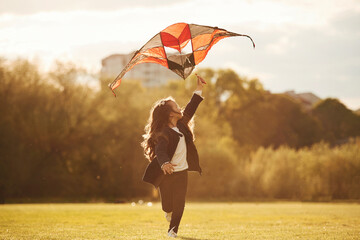 Beautiful sunlight. Happy little girl is playing with kite on the summer field