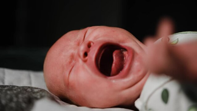 Newborn baby crying lying in the crib. New born kid tired and hungry in bed. Child crying lying at home