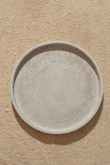 A gray stone dish on the sand. Background for cosmetics and food