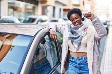 African american woman smiling confident holding key of new car at street