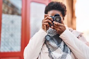 African american woman smiling confident using professional camera at street