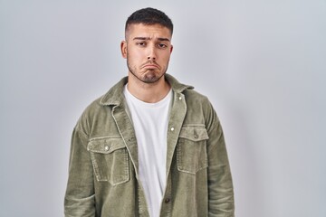 Young hispanic man standing over isolated background depressed and worry for distress, crying angry...
