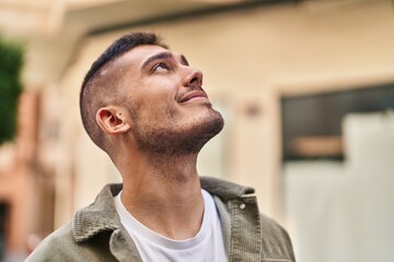 Young hispanic man smiling confident looking to the sky at street