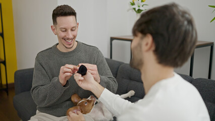 Two men couple smiling confident surprise with engagement proposal at home