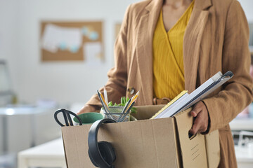 Close-up of businesswoman packing things in box while moving in new office
