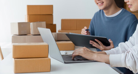 Happy couple people packing parcel boxes, couple lover checking order online on laptop at home