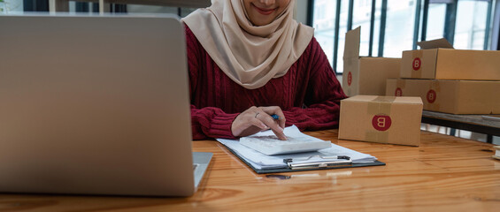 Close up muslim woman in hijab working online sales Checking for customer orders in office