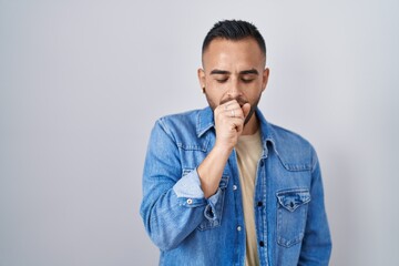 Young hispanic man standing over isolated background feeling unwell and coughing as symptom for cold or bronchitis. health care concept.