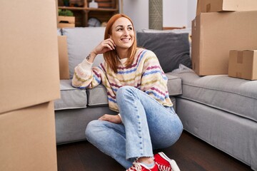 Young caucasian woman smiling confident sitting on floor at new home