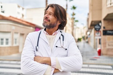 Middle age man doctor smiling confident standing with arms crossed gesture at street