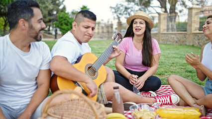 Group of people playing guitar having picnic at park