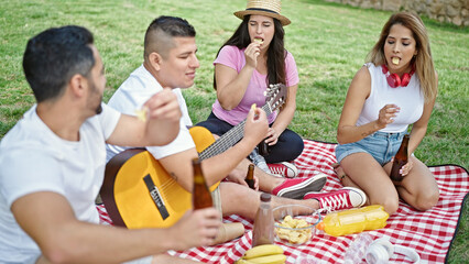 Group of people having picnic sitting on grass at park