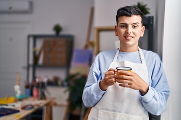 Young non binary man artist smiling confident drinking coffee at art studio