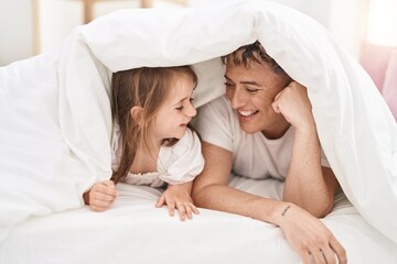 Father and daughter father and daughter lying on bed covering with bedsheet at bedroom