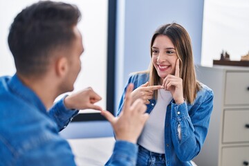 Man and woman couple communicate with deaf language sitting on sofa at home