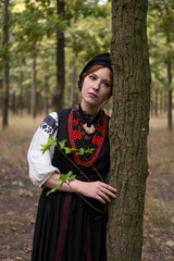 А woman in Ukrainian national embroidered dress vyshyvanka, outdoors in the forest. - 619778106