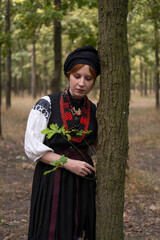 А woman in Ukrainian national embroidered dress vyshyvanka, outdoors in the forest. - 619778127