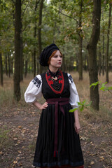 А woman in Ukrainian national embroidered dress vyshyvanka, outdoors in the forest.