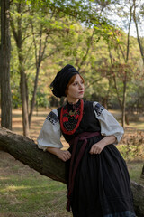 А woman in Ukrainian national embroidered dress vyshyvanka, outdoors in the forest. - 619778148